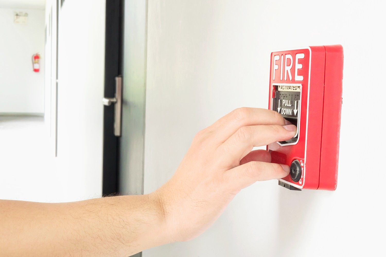 man is reaching his hand push fire alarm hand station