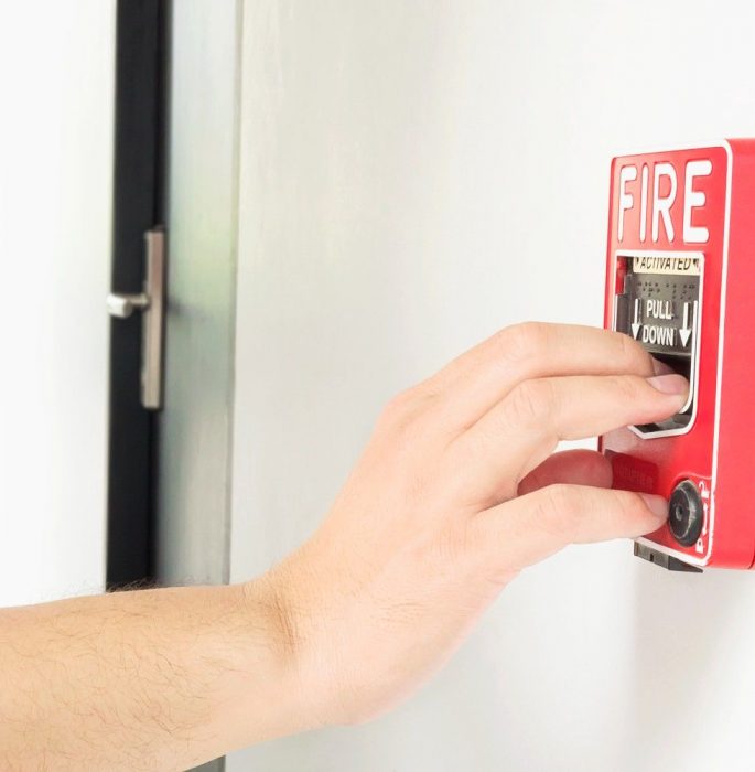 man is reaching his hand push fire alarm hand station